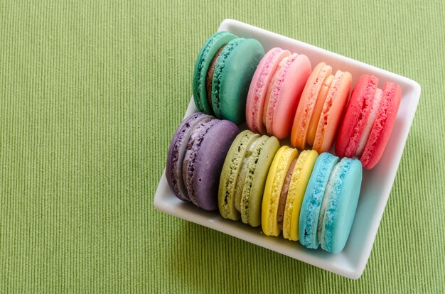 Kolorowi macarons na zielonym obrusie