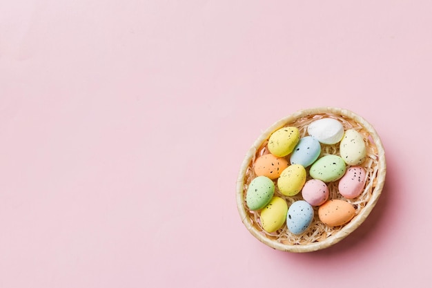 Kolorowi Wielkanocni jajka w łozinowym koszu przeciw kolorowemu tła zbliżenie odgórnemu widokowi z kopii przestrzenią