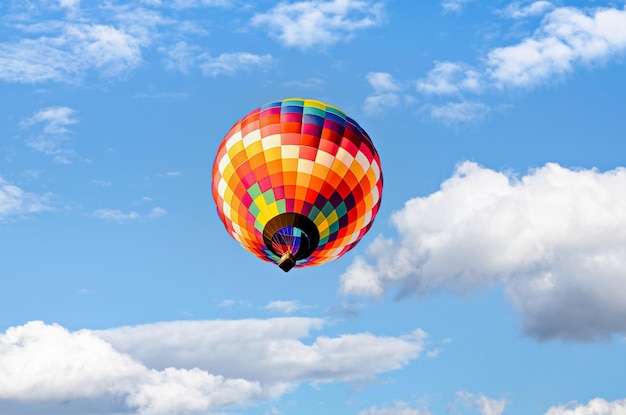 Kolorowy balon na ogrzane powietrze latające nad błękitne niebo z białymi chmurami.