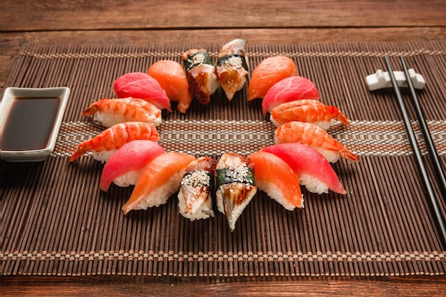 Kolorowy japoński zestaw sushi, owoce morza. Świetny asortyment nigiri nigiri podawanych jak koło na brązowej macie ze słomy, z bliska. Narodowe owoce morza, zdjęcie menu restauracji.