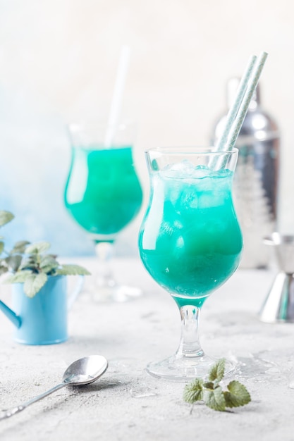 Kolorowy letni koktajl Blue Hawaii lub mrożony napój alkoholowy Blue Lagoon z miętą na jasnym kamiennym tle