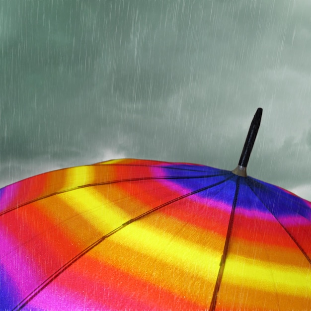 Kolorowy parasol z ulewnym deszczem i chmurami