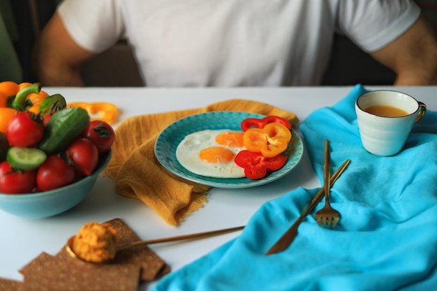 Kolorowy stół ze zdrową żywnością i kawą na śniadanie lub brunch oraz mężczyzna w białej koszulce