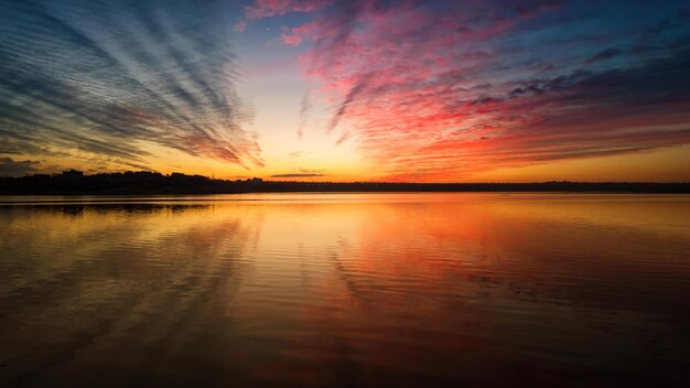 Kolorowy zachód słońca na rzece z odbiciem chmur w wodzie