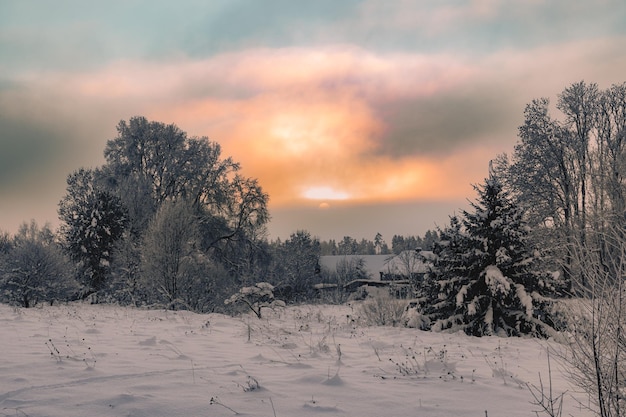 Kolorowy zachód słońca na wsi w zimowym słońcu idzie za chmurami