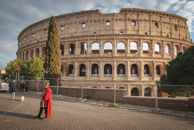 Zdjęcie koloseum w rzymie we włoszech o wschodzie lub zachodzie słońca z ulicznym artystą i turystami