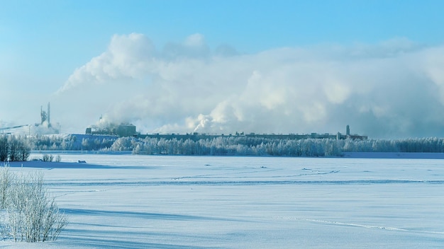 Komin fabryczny i para w zimowym krajobrazie w Laponii, Finlandia