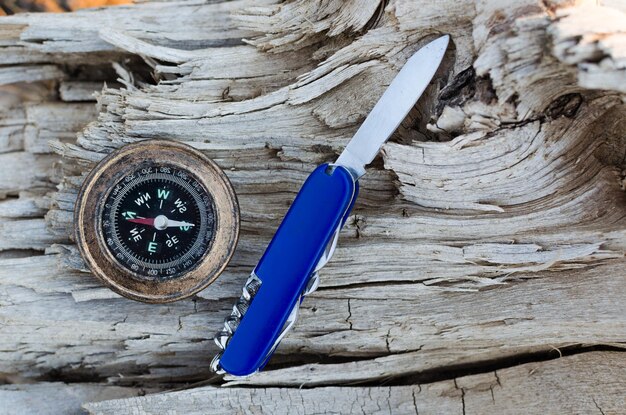 Zdjęcie kompas i nóż do przetrwania na starym wysuszonym drzewiezbliżenie