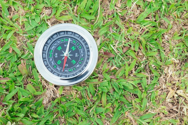Kompas jest umieszczony na zielonej trawie pokazującej północ południowy wschód zachód