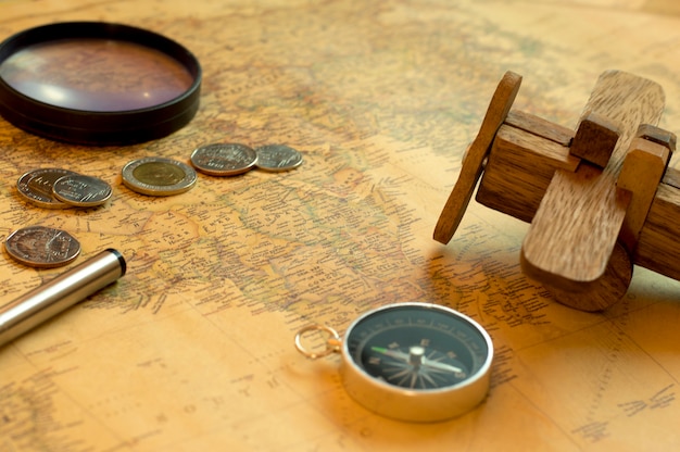Kompas, monety i drewniany samolot na mapie świata