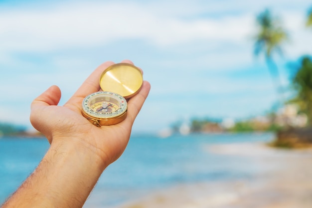 Kompas pod ręką w morzu i na plaży.