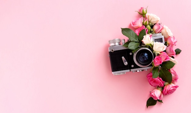 Kompozycja kwiatowa z wieńcem róż i aparatem na różowym tle. Walentynki tło. Leżał płasko, widok z góry.