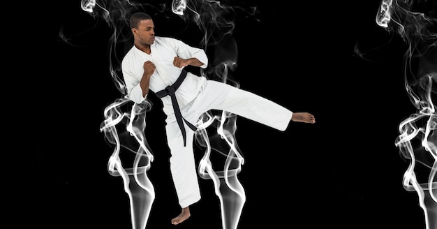 Kompozycja męskiego artysty karate walki z czarnym pasem kopiącym nad dymem i kopią przestrzeni