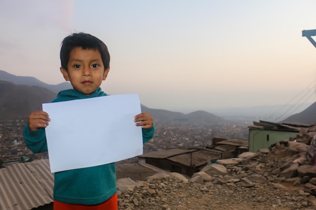 Kompozycja na Dzień Dziecka. Chłopiec trzymający pustą kartkę papieru, aby wstawić tekst lub wiadomość
