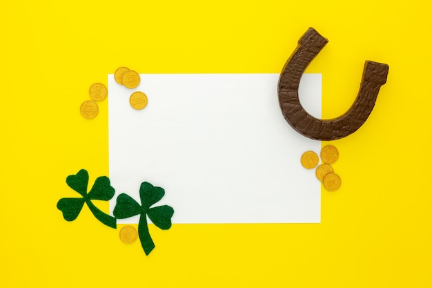 Zdjęcie kompozycja na dzień św. patryka. dekorowanie papieru zieloną koniczyną lub koniczyną, złotymi monetami i podkową