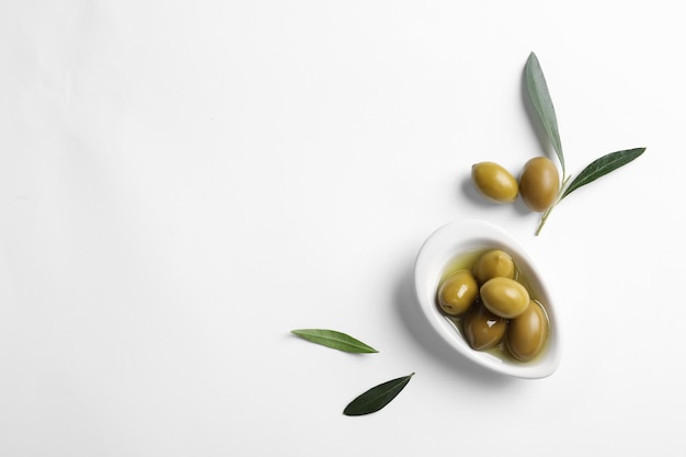 Kompozycja płaska ze świeżymi oliwkami w oleju na białym tle