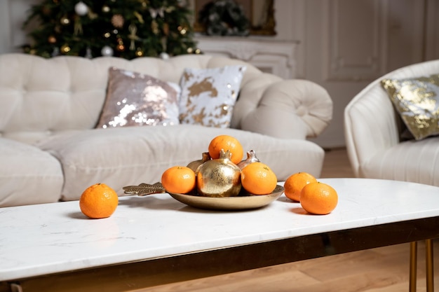 Kompozycja świąteczna martwa natura wystrój i mandarynki na marmurowym stole beżowa sofa i poduszki mandar