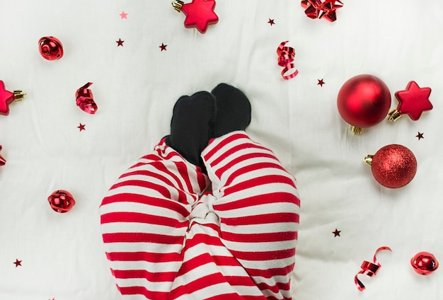 Kompozycja świąteczna Nogi noworodka w świątecznych ubraniach na białym tle