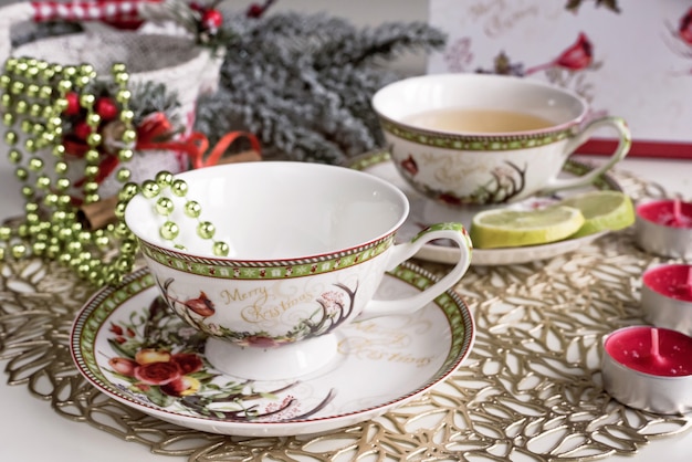 Kompozycja świąteczna z kwiatami i białymi filiżankami do herbaty