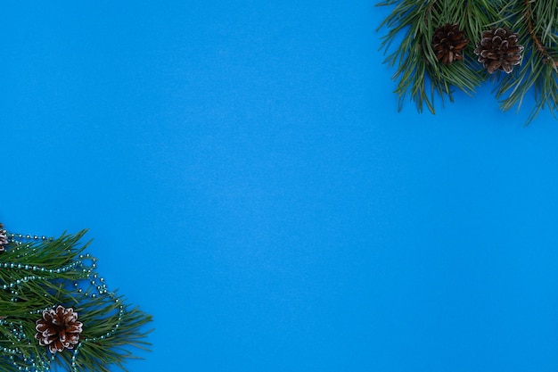 Kompozycja świąteczna zima Układ z gałęzi sosnowych koraliki i szyszki na niebieskim tle Koncepcja Bożego Narodzenia Flat lay