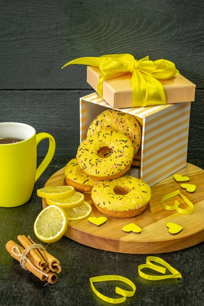 kompozycja świątecznej herbaty śniadaniowej i pączków na drewnianym tle w żółtych kolorach