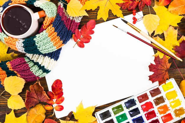 Kompozycja z arkuszem białego papieru maluje pędzle i jesienne kolorowe liście