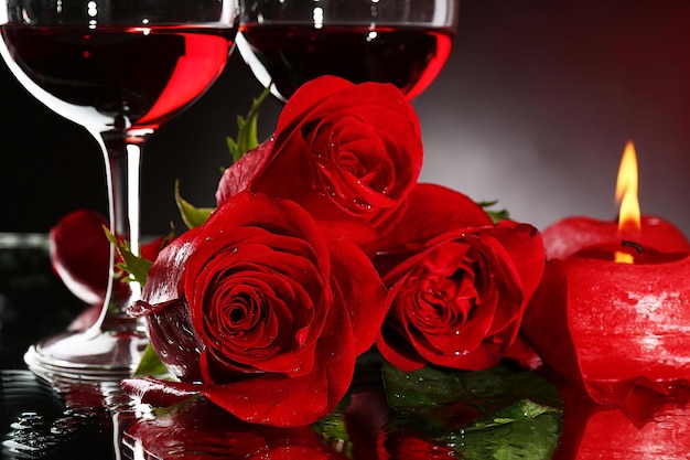 Kompozycja z czerwonym winem w kieliszkach, czerwoną różą i ozdobnym sercem na kolorowym tle