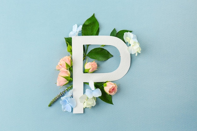 Kompozycja z literą P i pięknymi kwiatami na kolorowym tle