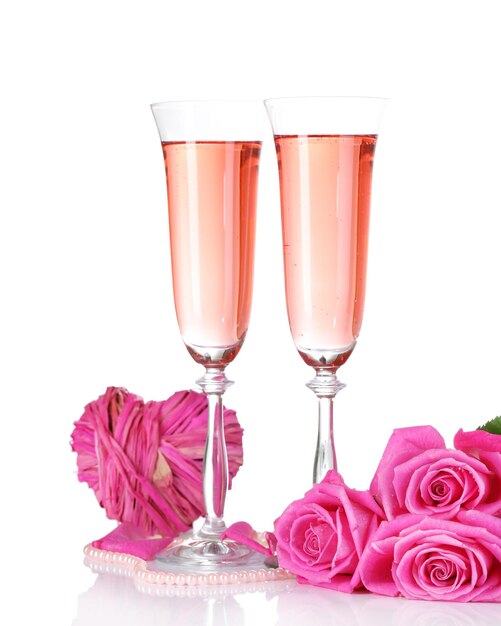 Kompozycja z różowym winem musującym w kieliszkach i różowymi różami na białym tle