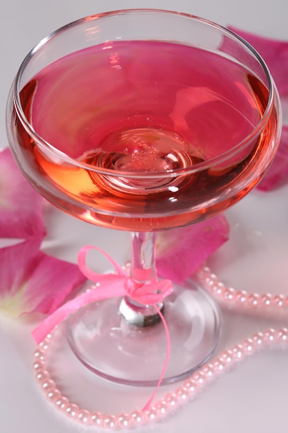 Zdjęcie kompozycja z różowym winem musującym w szkle i płatkami róż na białym tle