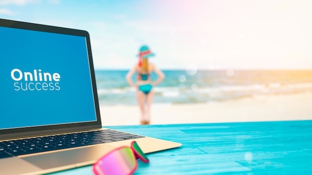 Zdjęcie komputer stoi na stole z widokiem na morze. a dziewczyna stoi zrelaksowana.