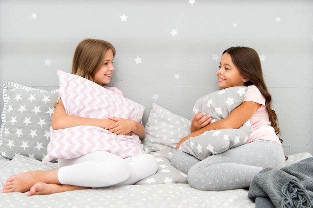 Komunikacja sióstr. Siostry komunikują się podczas relaksu w sypialni. Czas dla rodziny. Dzieci odpoczywają i bawią się wieczorem. Siostry wypoczynek. Dziewczyny w ślicznych piżamach spędzają razem czas w sypialni.
