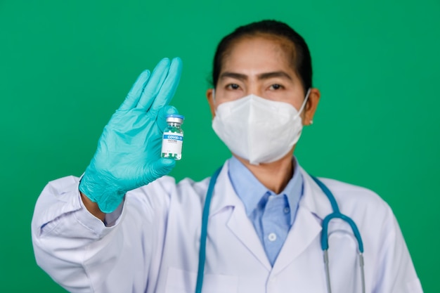 Koncentrując się na azjatyckiej lekarki noszącej fartuch laboratoryjny, trzymając strzykawkę i butelkę fiolki szczepionki Covid 19 Koncepcja szczepienia przeciwko Covid 19.