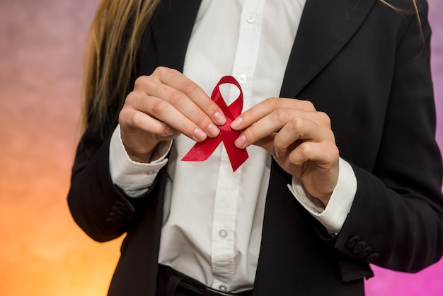 Koncepcja Aids. Kobieta Trzyma Czerwoną Wstążkę W Rękach Z Bliska