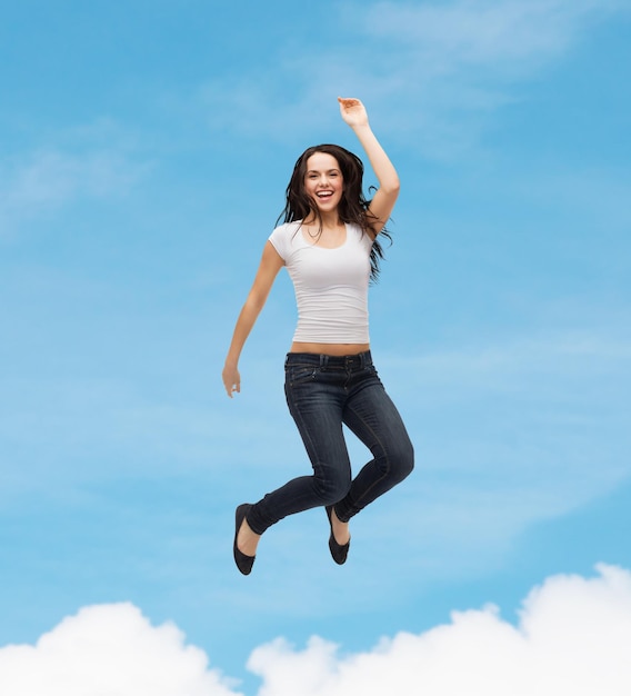 koncepcja aktywności i szczęścia - uśmiechnięta nastolatka w białej pustej koszulce skaczącej