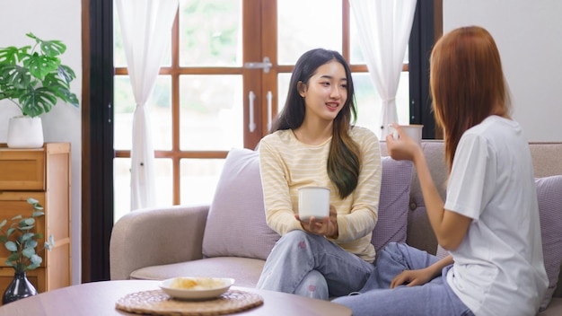 Koncepcja aktywności w domu Lesbijki LGBT siedzące na kanapie i pijące kawę podczas rozmowy