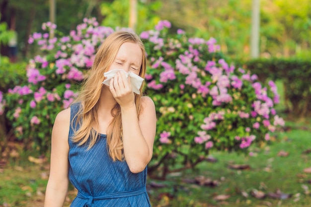 Koncepcja alergii na pyłki młoda kobieta będzie kichać kwitnące drzewa w tle