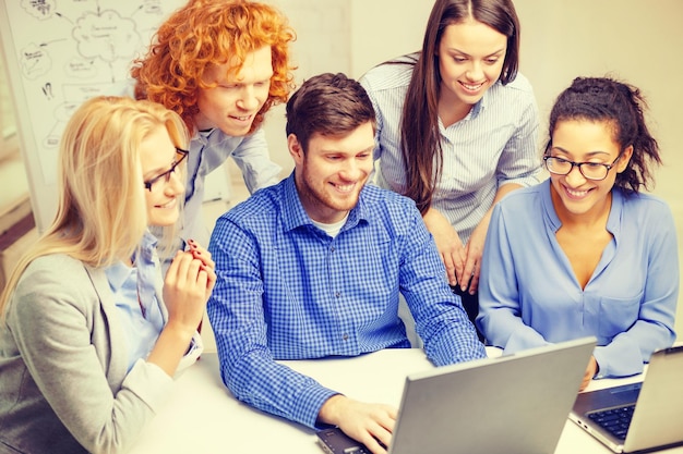 koncepcja biznesowa, biurowa i startupowa - uśmiechnięty kreatywny zespół z laptopami pracującymi w biurze