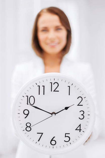 Zdjęcie koncepcja biznesowa, biurowa, szkolna i edukacyjna - atrakcyjna kobieta pokazująca zegar