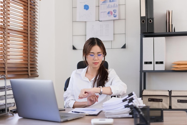 Koncepcja biznesowa Businesswoman to spojrzenie na czas na zegarku po ciężkiej pracy w biurze