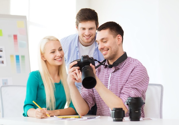 koncepcja biznesowa, edukacyjna, biurowa i startupowa - uśmiechnięty kreatywny zespół z aparatem fotograficznym pracujący w biurze