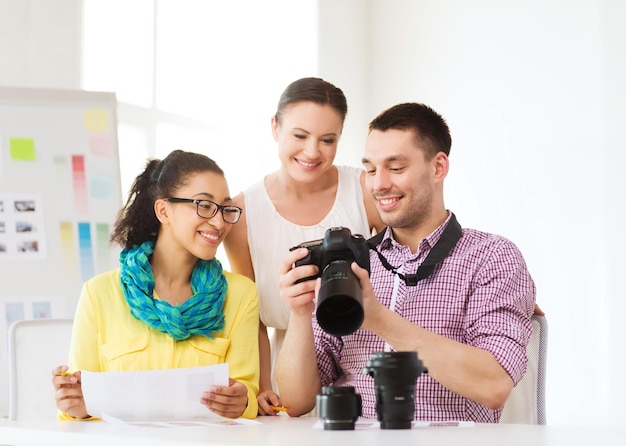 koncepcja biznesowa, edukacyjna, biurowa i startupowa - uśmiechnięty kreatywny zespół z aparatem fotograficznym pracujący w biurze