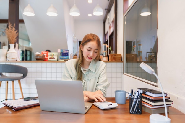 Koncepcja biznesowa Kobieta przedsiębiorca pracująca na laptopie z kalkulatorem w biurze przestrzeni coworkingowej