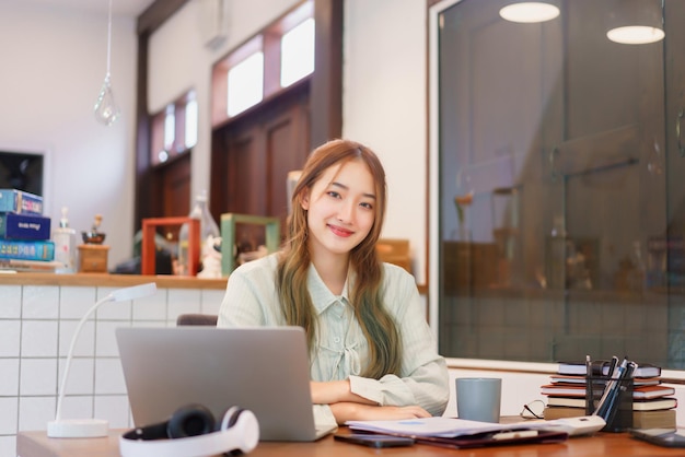 Koncepcja biznesowa Kobieta przedsiębiorca uśmiecha się i pracuje ze szczęściem w biurze przestrzeni coworkingowej