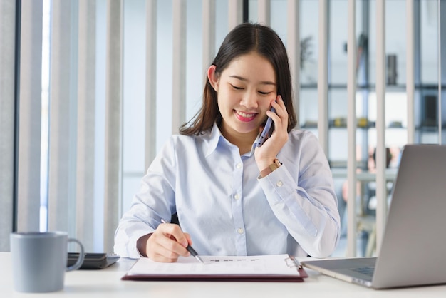 Koncepcja biznesowa Kobieta rozmawia przez telefon z partnerami w celu sprawdzenia informacji w dokumencie