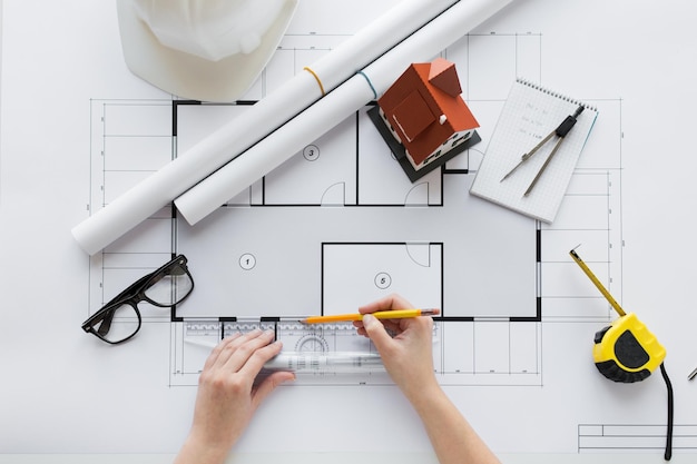 koncepcja biznesu, architektury, budownictwa, budownictwa i ludzi - zbliżenie rąk architekta z linijką i ołówkiem mierzącym plan domu mieszkalnego