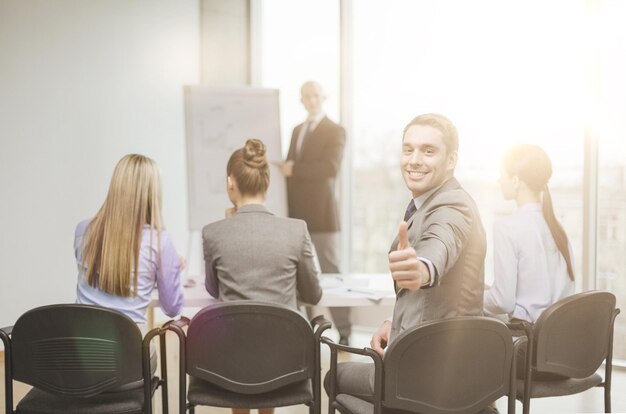 Zdjęcie koncepcja biznesu, biura i sukcesu - pewny siebie biznesmen z zespołem w biurze pokazującym kciuk w górę