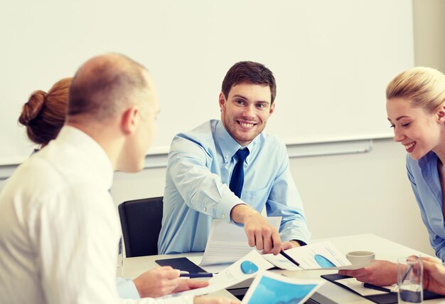 koncepcja biznesu, ludzi i pracy zespołowej - uśmiechnięty zespół biznesowy z dokumentami spotkanie w biurze