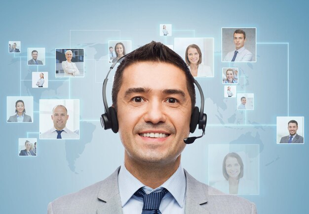 Koncepcja Biznesu, Ludzi, Technologii I Usług - Uśmiechnięty Biznesmen W Zestawie Słuchawkowym Nad Projekcją Wirtualnych Kontaktów Ikon I Niebieskim Tłem