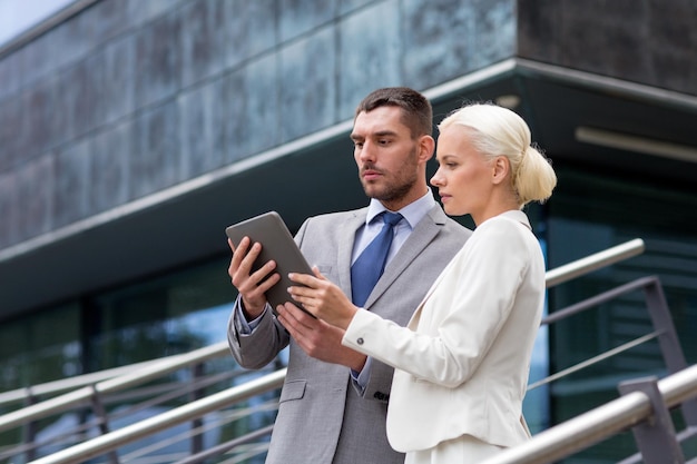 koncepcja biznesu, partnerstwa, technologii i ludzi - biznesmen i bizneswoman pracujący z komputerem typu tablet na ulicy miasta